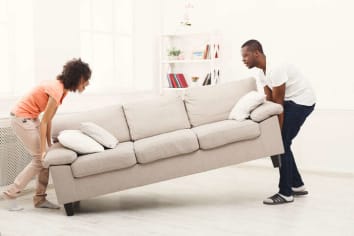 couple putting new sofa in home