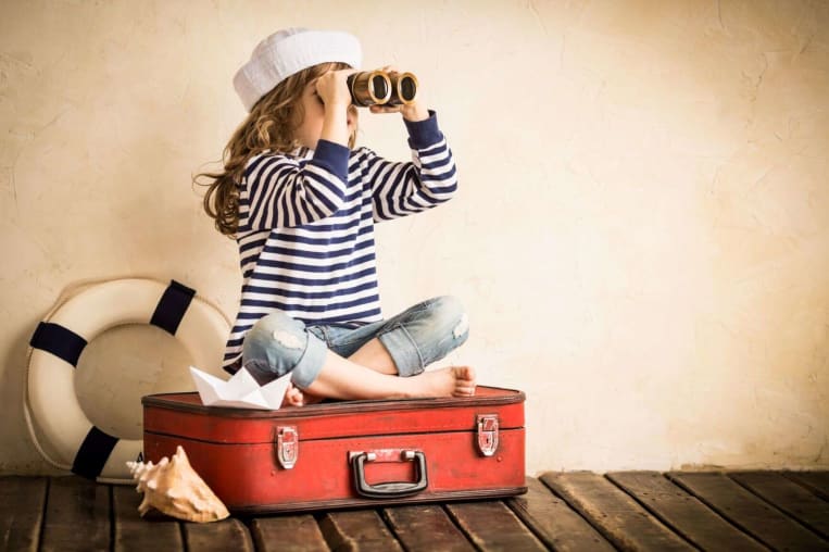 woman sitting on bag looking out of binoculars