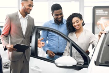 A couple is at a dealership looking at the inside of a car