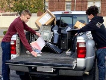 Two volunteers unloading electronics from a truck to be recycled