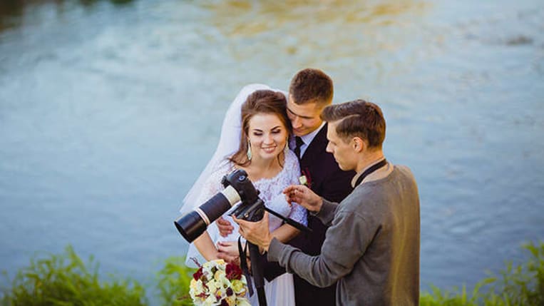 wedding couple standing with photographer