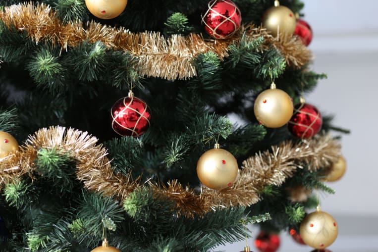 Artificial Christmas tree decorated with red-gold balls and tinsel. 