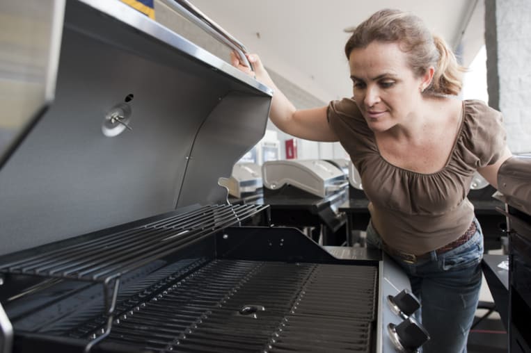 Woman opens the lid of a grill in a store