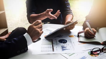 Business people sitting at table looking at charts