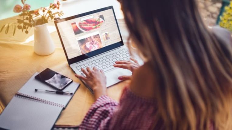 woman typing at table on laptop social media graphs content
