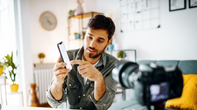 A marketing influencer shows off his new phone features to a live audience as his camera captures the presentation.