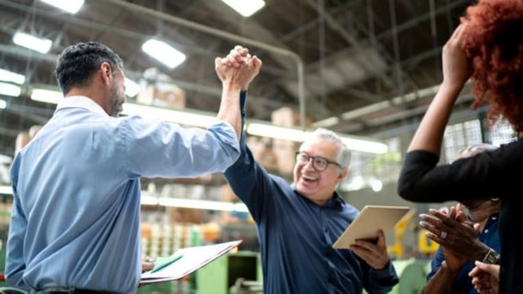 Small business manager and employees celebrating in a warehouse