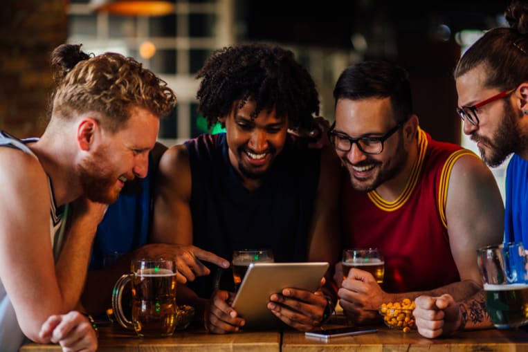 people clustered around a tablet at a sports pub