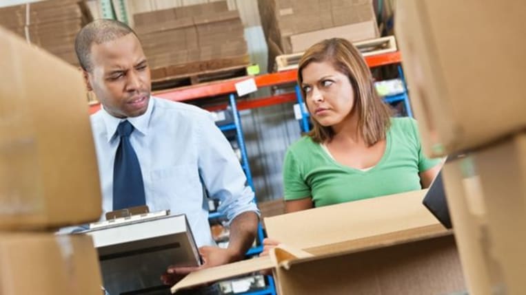 Two warehouse employees disagreeing with each other as they go over inventory