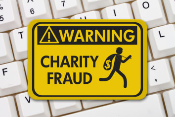 Charity Scam warning sign, A yellow warning sign with text Charity Fraud and theft icon on a keyboard