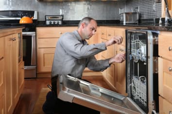 appliance repair person working on a dishwasher