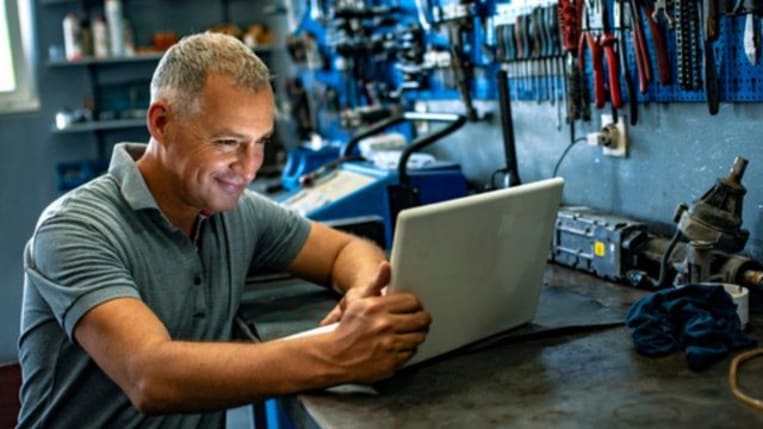 Small business owner working on his laptop in his tool shop.