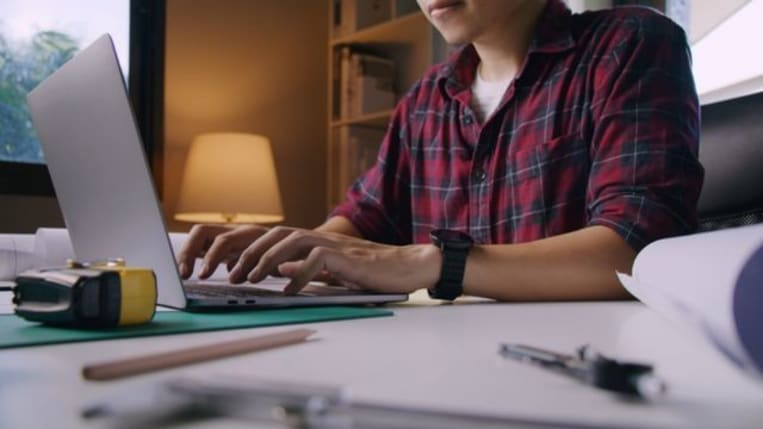 Small business owner typing on his laptop in his office.