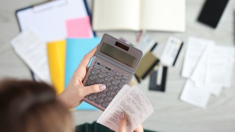 Business person holding a receipt and a calculator