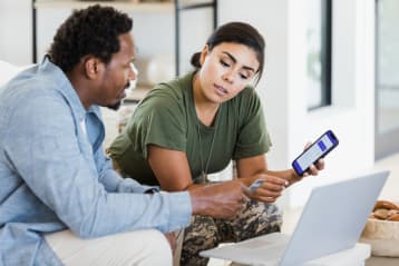 older man and younger woman looking at each other while he holds his phone