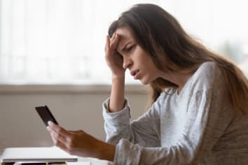 Frustrated young woman looking at smartphone