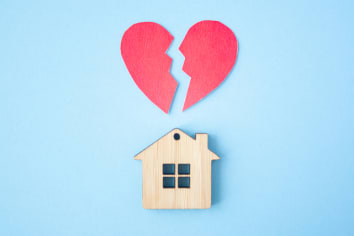 Divorce, division of property, poverty and no money concept. Wooden house with broken heart on bright blue background. Mortgage, rent, realtor