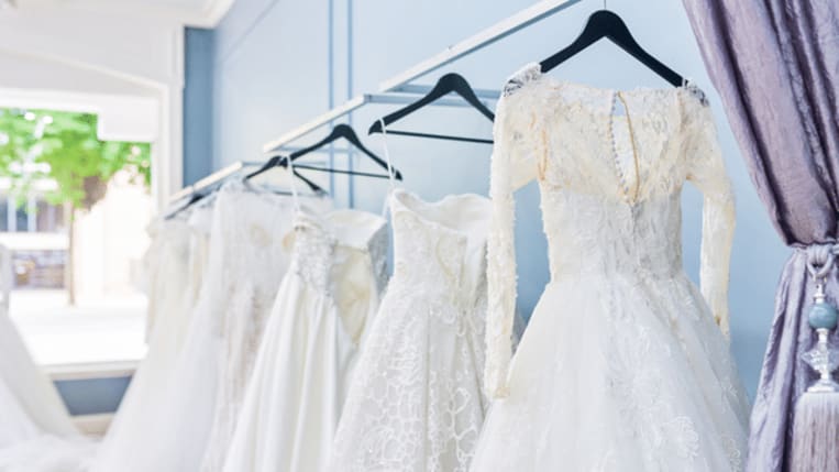 wedding dresses on black hangers against a blue background