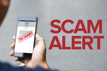 Man holding a phone opened on a text conversation. A red rectangle with the word "Scam!" is written on the phone. The words "Scam Alert" are written beside the phone.
