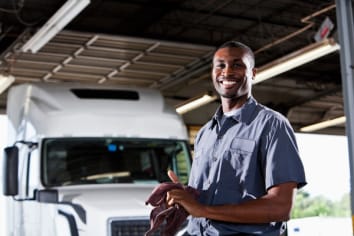 A happy big rig mechanic wipes his hands on a cloth.