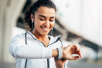woman smiling using a fitness tracker app before her workout