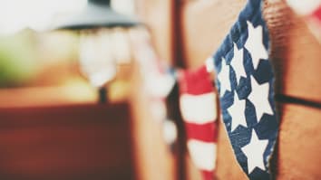 Close-up of an American flag patterned bunting hanging on a wood fence.