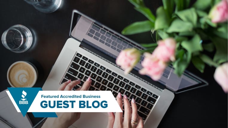 image of someone typing, with a cup of coffee and water on the left side, and pink flowers on the right. 