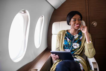 african american woman on plane listening to music on tablet