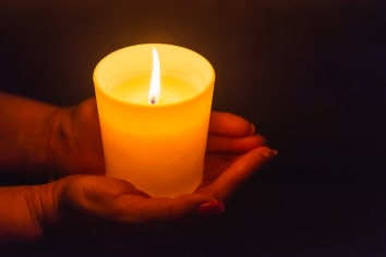 Candle in female hands on black dark background.Prayers candle in hands.�