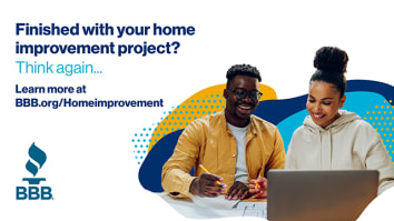 young african american couple smiling looking at home improvement plans and laptop