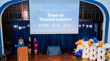 BBB Central Ohio Toast to Trusted Leaders gala, presenters standing behind podium on stage with blue curtains and blue, yellow, and white balloons with BBB sign