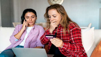 two females one on phone the other with credit card and laptop looking scared