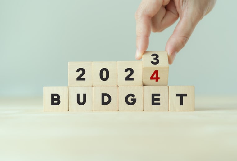 2024 Budget planning and allocation concept. Hand flips wooden cube and changes the inscription "BUDGET 2023" to "BUDGET 2024" with grey background, copy space. Use for banner and presentation.