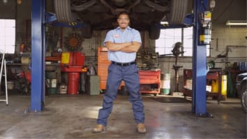Car mechanic standing in front of local auto body shop
