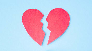 A pink paper cutout of a broken heart on a light blue background.