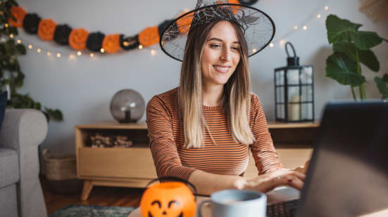 Young pregnant woman preparing for Halloween. She is decorating and shopping online.