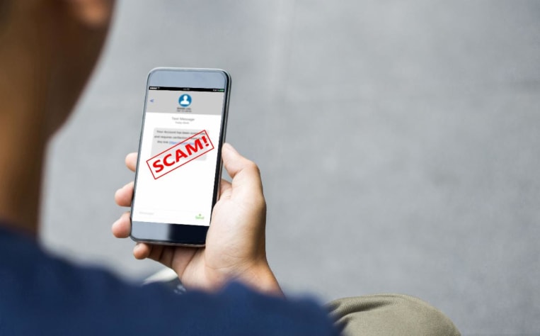 A person holding up a phone with a text from someone. The word scam is overlaid on top of the screen.
