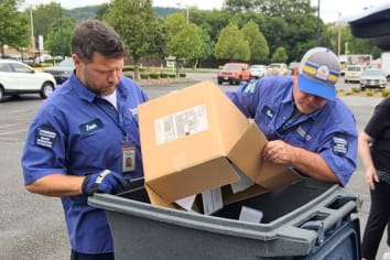 workers dumping documents into bin for shredding