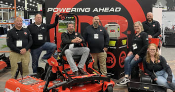The team of DR Power Equipment sitting on powered equipment at a tradeshow