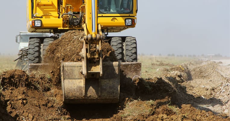 Excavator digging in dirt on property