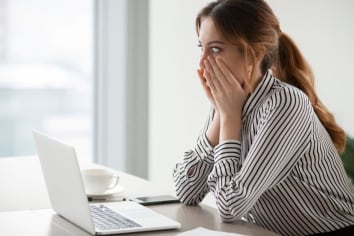 Woman looking worried at laptop.