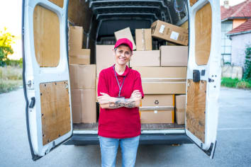 Van with packages and employee in red shirt standing in front of the open rear doors