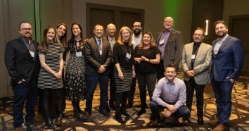 Thirteen of the staff on the Thayer Associates team at the CAI Awards. They are all dressed up and smiling in a group photo.