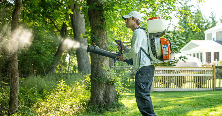 Darren from Mosquito Mike's spraying in backyard near treeline