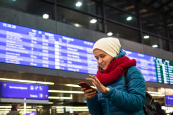 Young woman is booking railway ticket by using mobile app on her smartphone
