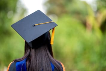 	closeup behind a female college graduate wearing a black fringe gown and a black hat, Concept of Successful Education in Hight School, Congratulated Degree