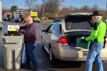volunteers unloading documents from a trunk and placing them in a large bin to be shred