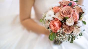 A close-up of a bride holding a bouquet of pink and white roses.