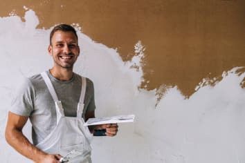 Portrait of a Happy Young Man Plastering Wall in his Workshop