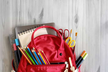 School backpack and school supplies on white wood table background. Back to school concept.